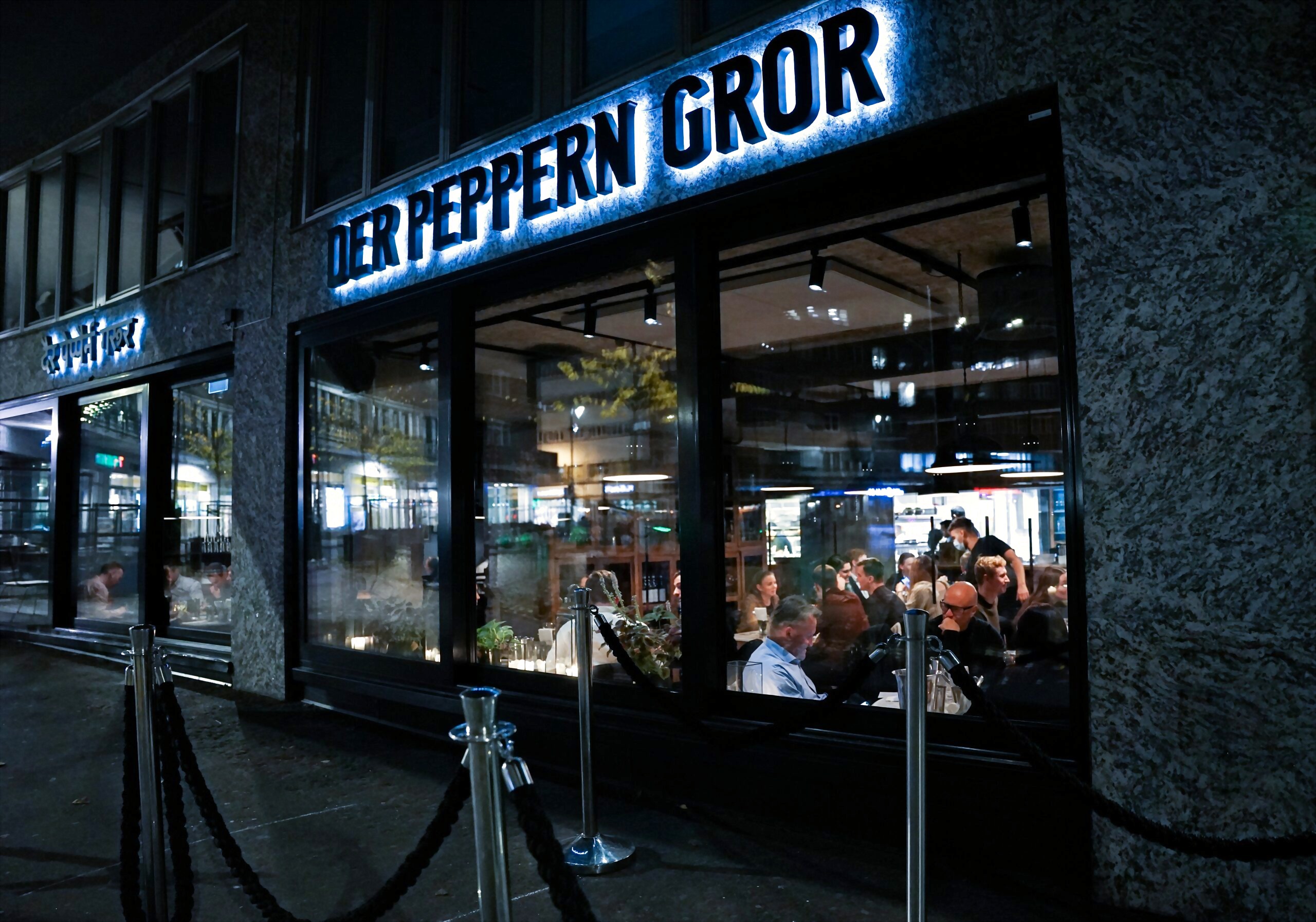 Der Peppern Gror om kvelden — varmt lys gjennom vinduene og gjester som spiser inne